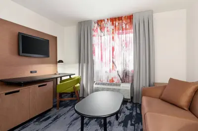 a hotel room with a couch and a desk and a chair at Fairfield Inn by Marriott Visalia Sequoia in Visalia