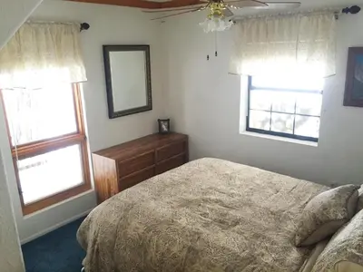 a bedroom with a bed and a dresser and two windows at Chateau Royal East in Yosemite West
