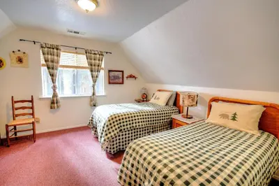 a bedroom with two beds and a chair and a window at Christmas Cabin in Yosemite West