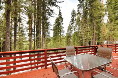 a table and two chairs on a deck with trees at Christmas Cabin in Yosemite West
