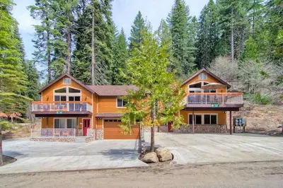 a large wooden house with a tree in front of it at Explorers Retreat in Yosemite West