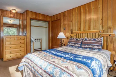 a bedroom with a bed with a wooden wall at Hutchings Cabin & Apt. in Yosemite West