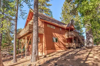 a cabin in the woods with a wrap around deck at Hutchings Cabin & Apt. in Yosemite West