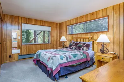 a bedroom with wooden walls and a bed and a window at Hutchings Cabin & Apt. in Yosemite West