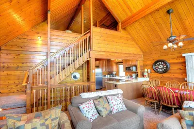 a living room with a couch and a kitchen at Treetops Cabin in Yosemite West