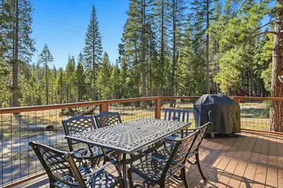 a table and chairs on a deck with trees at Apple Tree Bear House in Yosemite West