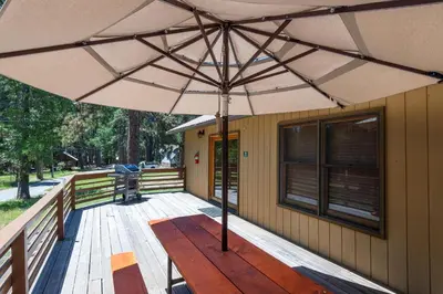a wooden table with an umbrella on a deck at Apple Tree Bear House in Yosemite West