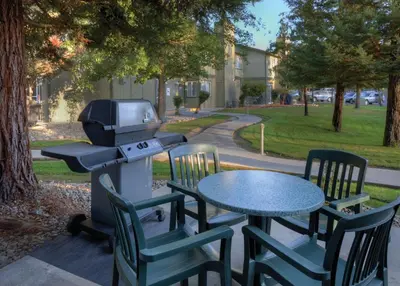 a grill and chairs with a table in a park at WorldMark Bass Lake in Bass Lake