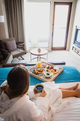 a woman laying on the floor in a room with a tray of food at Edgewood Tahoe Resort in Stateline