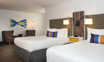 a hotel room with two beds and a chair at Hotel Becket, BW Signature Collection in South Lake Tahoe