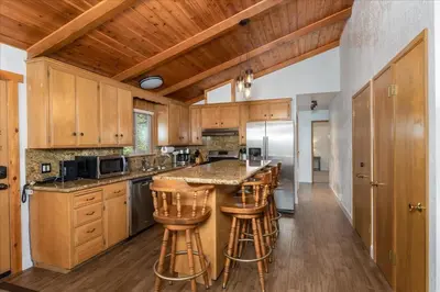 a kitchen with wooden cabinets and a island with bar stools at Evergreen in Wawona