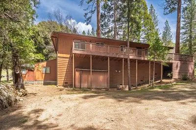 a house with a balcony in the woods at Evergreen in Wawona