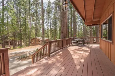 a wooden deck with a table and chairs on it at Evergreen in Wawona