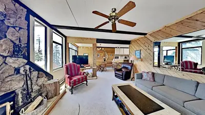 a living room with a ceiling fan and a stone wall at Great Condo With Free Shuttle to the Village! in Mammoth Lakes