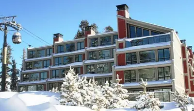 a building with snow in front of a ski lift at Great Condo With Free Shuttle to the Village! in Mammoth Lakes