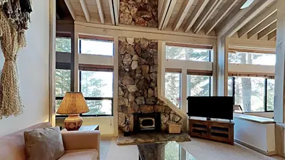 a living room with a stone fireplace and a television at Comfortable 4 Bedroom Condo in Mammoth Lakes