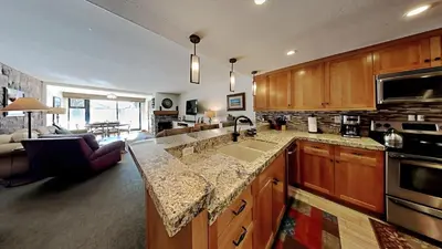 a kitchen with a sink and a living room at Renovated 2 Bedroom Condo with Elevator Access! in Mammoth Lakes