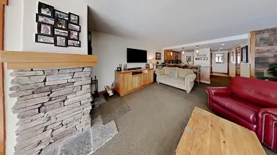 a living room with a red couch and a stone fireplace at Renovated 2 Bedroom Condo with Elevator Access! in Mammoth Lakes