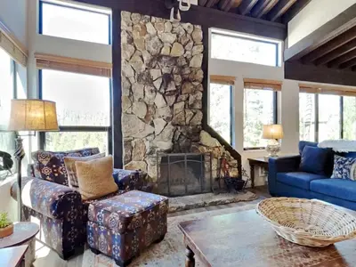 a living room with a large stone fireplace at Remodeled Spacious Cozy Condo Great For Families! in Mammoth Lakes
