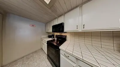 a small kitchen with white cabinets and black appliances at Beautiful 2 BR Condo with Mountain View! in Mammoth Lakes