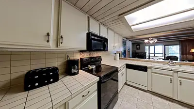 a kitchen with white cabinets and a black stove top oven at Beautiful 2 BR Condo with Mountain View! in Mammoth Lakes