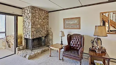 a living room with a stone fireplace and a chair at Comfortable Cozy 2 Bedroom Condo with Loft! in Mammoth Lakes