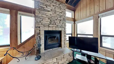 a living room with a stone fireplace and a television at Beautifully Remodeled 4 Bedroom Condo in Mammoth Lakes