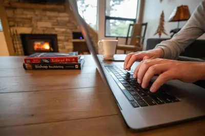 a person typing on a laptop computer on a table at Beautiful 4 Bed Condo with Top Of The Hill Views! in Mammoth Lakes