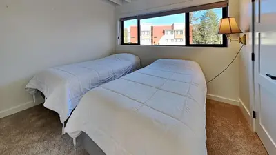 two beds in a small bedroom with a window at Large Spacious Upgraded 4 Bedroom Condo in Mammoth Lakes