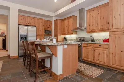 a kitchen with wooden cabinets and a island with bar stools at Lodges 1140- Spacious Townhome on Golf Course in Old Mammoth