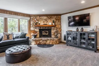 a living room with a stone fireplace and a television at Mountainback 15 in Old Mammoth