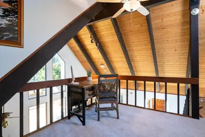 an attic room with a desk and a ceiling fan at North Shore - Cozy Cabin in Wood Vista