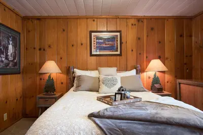 a bedroom with wooden walls and a bed with two lamps at North Shore - Dancing Antler in Wood Vista