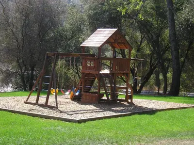 a wooden playground with a swing set in a park at Ponderosa Camping Resort One-Bedroom Cabin 2 in Lotus