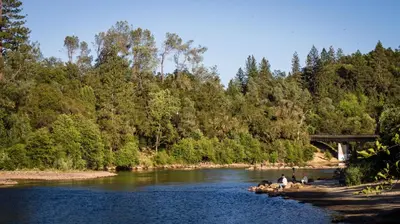 a group of people on rocks in a river with a bridge at Ponderosa Camping Resort One-Bedroom Cabin 4 in Lotus