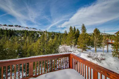 a wooden balcony with snow on the trees at Hillside View Home in Truckee