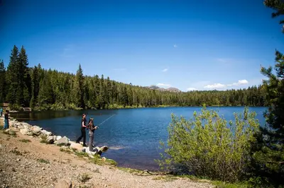 a man and a woman and a dog standing next to a lake at Snowflower Camping Resort Cottage 7 in Emigrant Gap