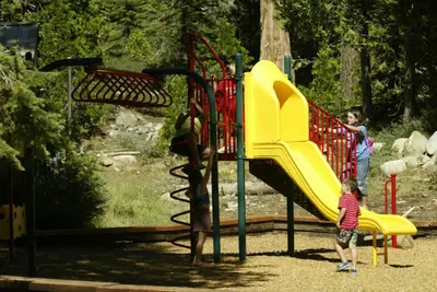 a group of children playing on a playground at Snowflower Camping Resort Cottage 7 in Emigrant Gap