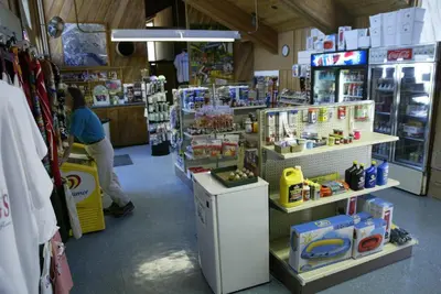 a store with a woman sitting at a counter in a store at Snowflower Camping Resort Cottage 7 in Emigrant Gap