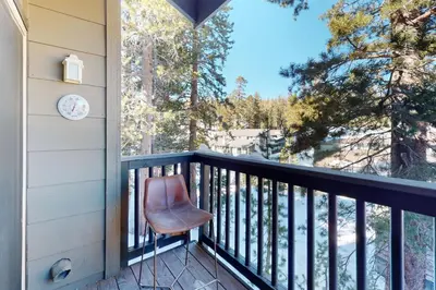 a chair sitting on a balcony with a view of trees at Chamonix 100 in Mammoth Lakes