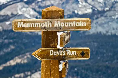 a wooden sign for mountaincolmthritis and dogs run at Helios North in Mammoth Lakes