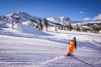 a person is skiing down a snow covered slope at Mammoth Green 101 in Mammoth Lakes