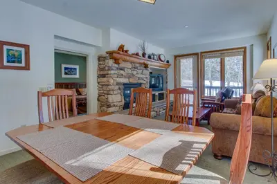 a living room with a table and a stone fireplace at Mammoth Green 101 in Mammoth Lakes