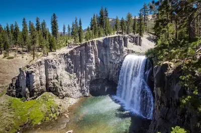 a waterfall on the side of a mountain with trees at The Summit 67 in Old Mammoth