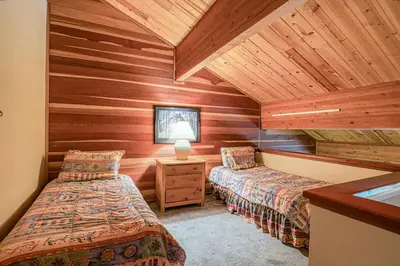 two beds in a room with wooden walls at The Bridges 23 in Mammoth Lakes