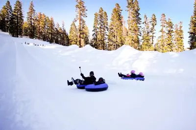 three people are riding down a snow covered slope on snowboards at Snowcreek 590 in Mammoth Lakes