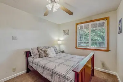 a bedroom with a bed with a ceiling fan and a window at Charming Tahoe Chalet in Tahoe Valley