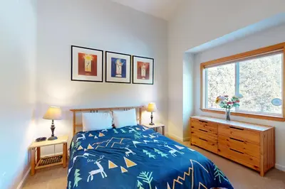 a bedroom with a bed with a blue comforter and a window at Squaw Valley Ski Flat in Olympic Valley