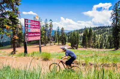 a man riding a bike on a dirt road next to a sign at Aspen Grove Studio at Northstar in Truckee