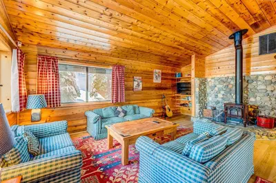 a living room with blue couches and a wooden ceiling at Ford Family Escape in Truckee